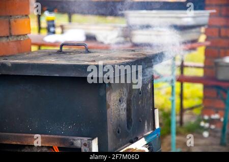 le processus de fumer du poisson ou de la viande. fumeur de l'extérieur pour le poisson et la viande. la fumée provient d'une boîte noire pour la préparation des aliments fumés. Banque D'Images