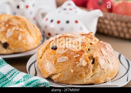 Gâteau sucré maison fraîchement cuit avec amandes et raisins secs sur une table en bois. Pain de Pâques. Panier avec poires et pommes. Théière et tasse de thé de couleur Banque D'Images