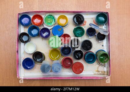 Une boîte avec de vieux pots ouverts de gouache pour la peinture. Vue de dessus des pots à moitié vides de peintures à la gouache. Disposition plate sur la table. Banque D'Images