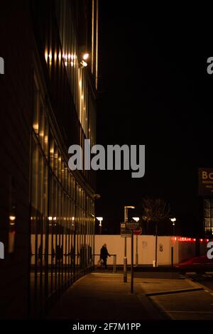 Silhouette d'une personne qui marche dans l'obscurité à travers Media City, Salford Banque D'Images