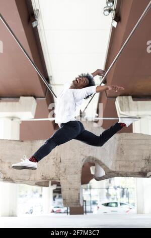 Danseuse afro-américaine effectuant un saut acrobatique dans la ville en plein air. Concept de danse urbaine. Espace pour le texte. Banque D'Images