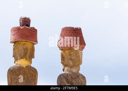 Vue arrière des têtes de moai restauré avec des noeuds rouges de scories (pukao) sur AHU Nao-Nao, Plage d'Anakena sur la côte nord de l'île de Pâques (Rapa Nui) Banque D'Images