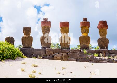 Vue arrière des têtes de moai restauré avec des noeuds rouges de scories (pukao) sur AHU Nao-Nao, Plage d'Anakena sur la côte nord de l'île de Pâques (Rapa Nui) Banque D'Images