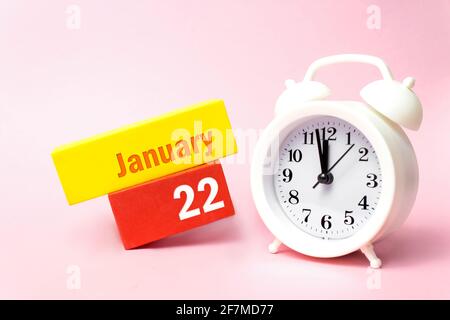 22 janvier. Jour 22 du mois, date du calendrier. Réveil blanc sur fond rose pastel. Concept mois d'hiver, jour de l'année Banque D'Images