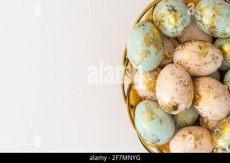 Œufs de Pâques colorés dans un panier isolé sur fond blanc et copier l'espace sur le côté gauche Banque D'Images