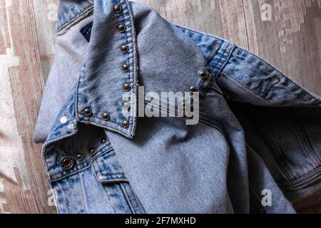 Gros plan d'une veste en denim pliée en deux sur une planche de lit dorée. Veste avec boutons argentés, look jean bleu pâle, Ontario, Canada. Banque D'Images