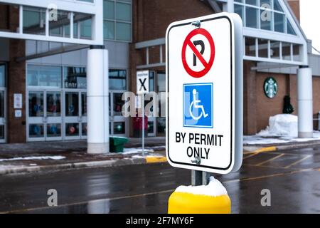 London, Ontario, Canada - février 15 2021 : pas de stationnement, par permis seulement, panneau portant le symbole d'accès international sur un panneau vertical rectangulaire. Banque D'Images