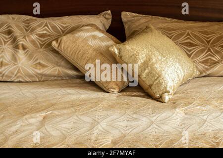 Deux coussins carrés dorés qui brillent au soleil, assis sur une couette à motifs dorés assortis dans une chambre de l'Ontario, au Canada. Banque D'Images