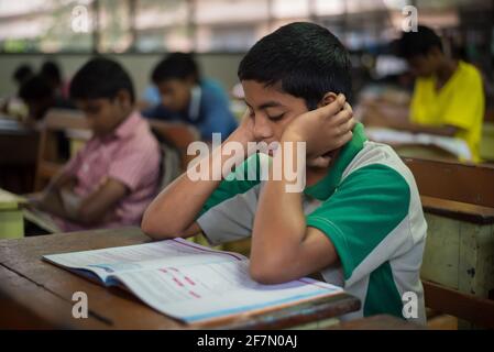 Varanasi, Inde. 10-14-2019. Un enfant lisant dans une école d'embarquement faisant ses devoirs après le dîner en Inde. Banque D'Images