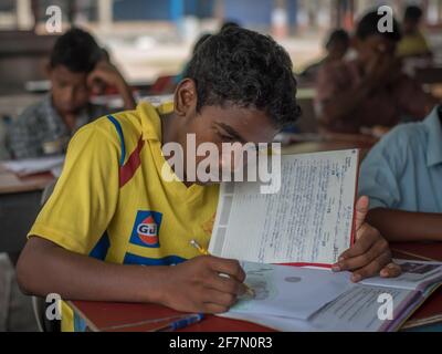 Varanasi, Inde. 10-14-2019. Un adolescent de sexe masculin écrit sur son manuel dans une école d'embarquement tout en faisant ses devoirs. Banque D'Images