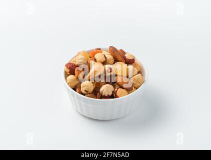 Un mélange de noix et de fruits secs dans un bol blanc sur fond clair. Vue latérale, gros plan. Banque D'Images