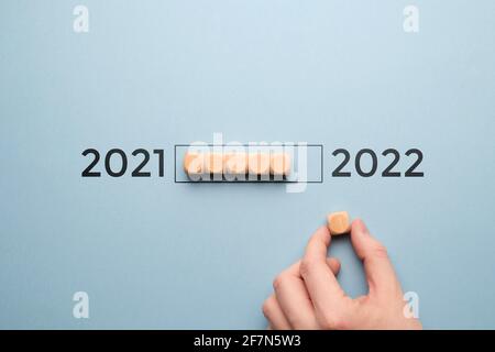 Concept pour la transition de l'année de 2021 à 2022 sur des cubes en bois avec une barre de chargement. Banque D'Images