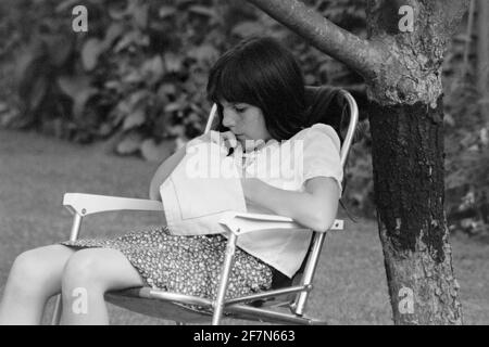 jeune fille se concentrant sur la couture dans le jardin early1980 royaume-uni Banque D'Images