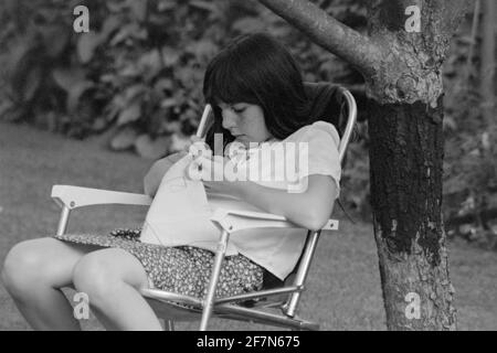 jeune fille se concentrant sur la couture dans le jardin early1980 royaume-uni Banque D'Images