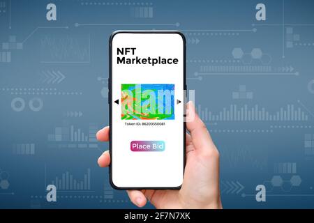 Une main tient un smartphone avec un type de cryptographique NFT Marketplace art avec place BID Banque D'Images