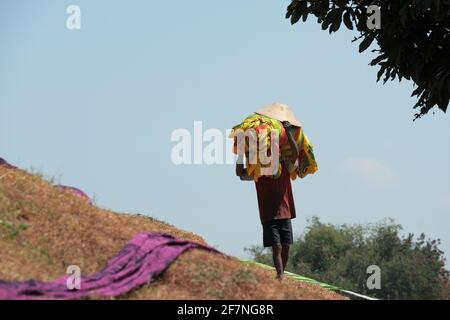 Homme portant une pile de vêtements sur sa tête, travailleur de l'industrie textile de Mojolaban pareo Banque D'Images