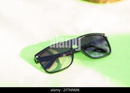 Lunettes de soleil classiques pour hommes et femmes avec verres noirs et cadre noir Shoot à l'extérieur dans une journée d'été gros plan. Mise au point sélective Banque D'Images