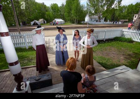 Pleine corps heureux philippin voyageur et femme dans la vieille mode costume souriant et regardant la caméra tout en se tenant près de la clôture À fort Edmonton, en Alberta Banque D'Images