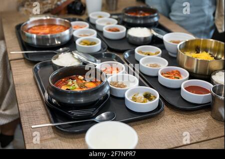 Divers plats coréens avec soupe épicée, kimchi, nouilles et pickle aux légumes sur le plateau du restaurant Banque D'Images