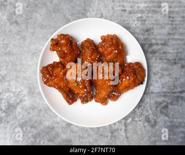 Vue de dessus poulet coréen épicé au friture surmontée de sésame blanc sur la table en béton gris, cuisine populaire de la rue en Corée. Banque D'Images