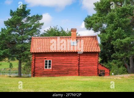 Chalet confortable en bois rouge avec une journée d'été lumineuse et ensoleillée à Åland, Finlande Banque D'Images