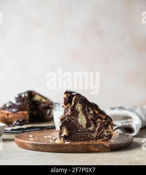 Morceau de gâteau en marbre fait maison avec glaçage au chocolat et noix sur une assiette en bois. Tarte au zébrée au chocolat et à la vanille. Mise au point sélective. Banque D'Images