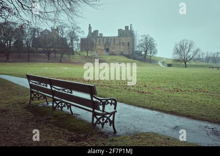 Banc en premier plan dans le parc et un vieux château écossais au lever du soleil. Palais de Linlithgow, Écosse Banque D'Images