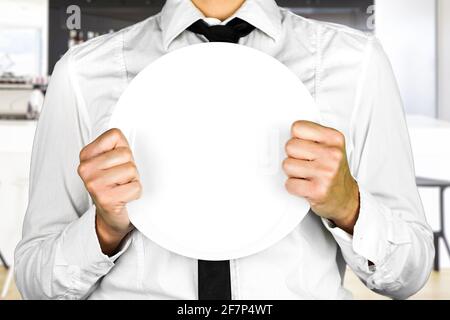 Une plaque vide tenue par un serveur sans visage. Photo parfaite pour la cuisine, pas de clients, pandémie, travail. Banque D'Images