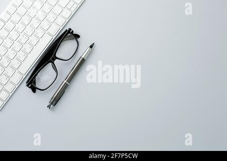 Stylo à lunettes et clavier blanc sur fond blanc Banque D'Images
