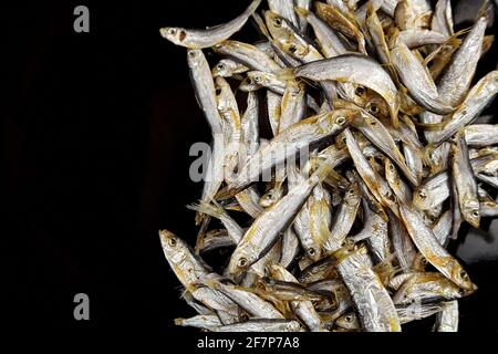 Petit poisson salé séché sur fond noir, vue de dessus, espace de copie. Banque D'Images