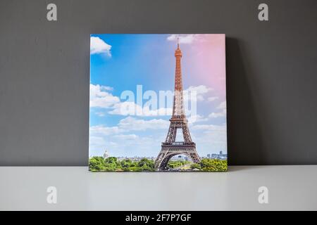 Imprimé toile étiré sur le cadre avec papier cadeau. Photographie avec Paris Tour Eiffel paysage urbain sur une surface blanche et un fond de mur gris, photo prin Banque D'Images