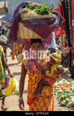 Koraput, Inde - février 2021: Femme d'Adivasi de la tribu Kondh avec son enfant magasiner des légumes dans le marché de Koraput le 21 février 2021 à OD Banque D'Images