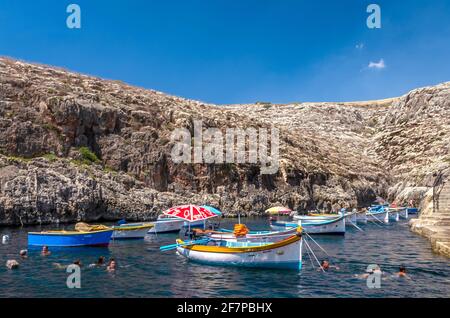 Malte, Wied iz-Zurrieq: Les gens nagent et ont peint gaious vieux bateaux de pêche dans le port près de la Grotte bleue. Banque D'Images