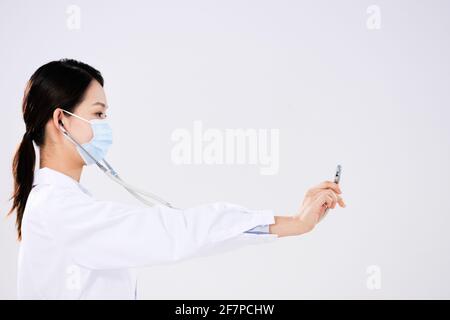 Une femme médecin portant un masque utilise un côté stéthoscope vue