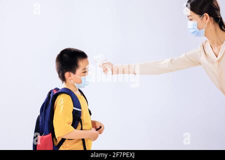 Le petit garçon a pris sa température avant l'école par son maman Banque D'Images