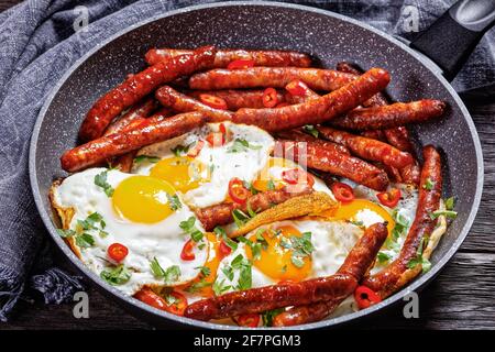 Longaniza con huevos, petit déjeuner de saucisses avec des œufs frits dans une poêle sur une table en bois, vue horizontale d'en haut, cuisine mexicaine Banque D'Images