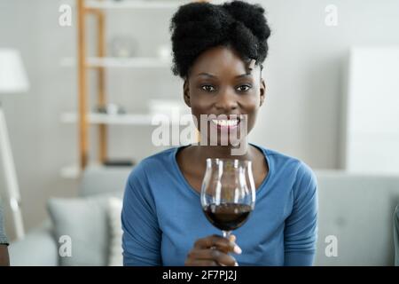 Femme buvant du vin rouge dans la vidéoconférence à la maison Banque D'Images