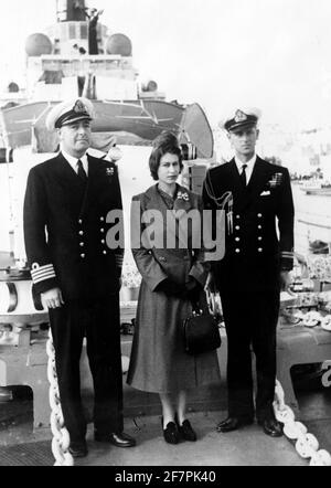 Photo du dossier datée du 26/12/49 du duc d'Édimbourg et du capitaine John Edwin Home McBeath DSO, DSC, RN (à gauche), pose avec la reine Elizabeth II pour une photographie sur le HMS Checkers, lors de la visite du destroyer le lendemain de Noël sur lequel le duc sert actuellement. Philip a rejoint la Marine après avoir quitté l'école et, en mai 1939, il s'est inscrit au Royal Naval College de Dartmouth, où il a été désigné comme meilleur cadet. Il a rapidement augmenté à travers les rangs, gagnant la promotion après la promotion, mais sa vie a été de prendre un cours très différent. La carrière navale florissante de dukeÕs a pris fin prématurément en 1951. Philip Banque D'Images