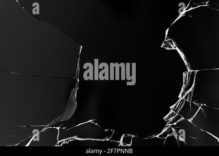 Fissures dans le verre, avec trous de balles sur fond noir. Banque D'Images