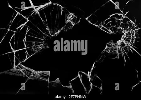 Fissures dans le verre, avec trous de balles sur fond noir. Banque D'Images