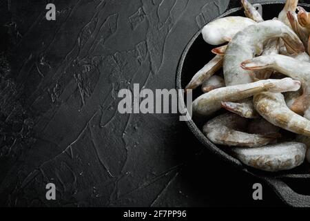 Carapace surgelée sur les crevettes tigrées ou crevettes tigrées asiatiques, dans une poêle à frire en fonte, sur fond de pierre noire, avec espace pour le texte Banque D'Images