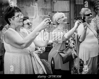 Groupe de femmes amusées par un interprète dans la rue prenant des photos Banque D'Images