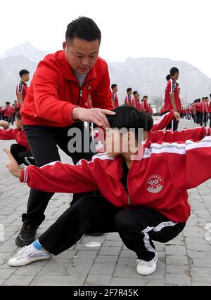 (210409) -- DENGFENG, 9 avril 2021 (Xinhua) -- Fang Yuhao (avant R) de l'équipe de hockey sur glace Shaolin Tagou est instruit par l'entraîneur pendant la classe d'arts martiaux à l'école d'arts martiaux Shaolin Tagou, Dengfeng City, dans la province de Henan, au centre de la Chine, le 30 mars 2021. Shaolin Tagou Martial Arts School, à quelques kilomètres du temple de Shaolin, lieu de naissance de Shaolin Kung Fu, construit son équipe de hockey sur glace. Les élèves apprennent le sport sur des patins à roulettes dans une patinoire de taille standard recouverte de plancher, au lieu de glace. La pratique des arts martiaux renforce leur physique et leur fournit un qual athlétique Banque D'Images