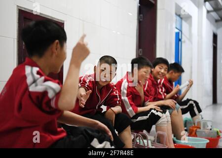 (210409) -- DENGFENG, le 9 avril 2021 (Xinhua) -- Huang Yuxuan (2e L) de l'équipe de hockey sur glace de Shaolin Tagou communique avec ses colocataires dans leur dortoir de l'école d'arts martiaux de Shaolin Tagou, Dengfeng City, dans la province de Henan, au centre de la Chine, le 31 mars 2021. Shaolin Tagou Martial Arts School, à quelques kilomètres du temple de Shaolin, lieu de naissance de Shaolin Kung Fu, construit son équipe de hockey sur glace. Les élèves apprennent le sport sur des patins à roulettes dans une patinoire de taille standard recouverte de plancher, au lieu de glace. La pratique des arts martiaux renforce leur physique et leur fournit un qualit athlétique Banque D'Images