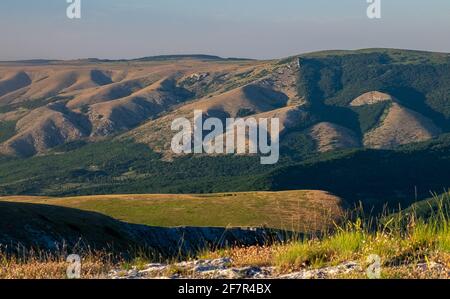 PID aux montagnes environnantes du plateau inférieur de Chatyr-Dag en Crimée à la lumière du soleil couchant. Banque D'Images