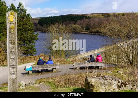 Panneau de chemin public en bois indiquant le réservoir de Thruscross avec des touristes assis sur des bancs profitant de la vue, Washburn Valley, Harrogate, Royaume-Uni. Banque D'Images