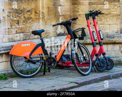 Location de scooters et de vélos électriques dans une rue du centre historique de Cambridge. VOI Technology e-trottinettes et e-Bikes dans une rue de Cambridge Banque D'Images