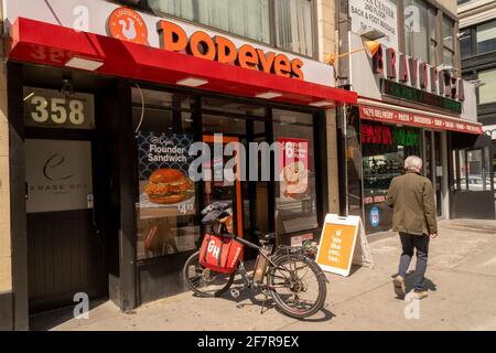Un vélo de livraison avec un fourre-tout de marque GrubHub se tient à l'extérieur d'un restaurant de restauration rapide Popeye's Louisiana Kitchen dans le quartier de Nomad à New York le dimanche 4 avril 2021. (© Richard B. Levine. Banque D'Images