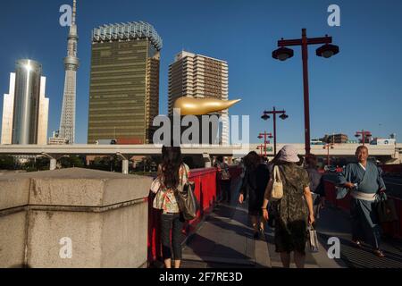 Plan horizontal de quelques passants sur le pont Azuma-Bashi au-dessus de la rivière Sumida avec le Tokyo Sky Tree et la flamme Asahi en arrière-plan, Asakusa Banque D'Images