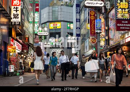 Vue horizontale à angle bas de la foule traversant les restaurants plein de panneaux colorés au néon sur Shibuya Center-gai, Shibuya, Tokyo, Japon Banque D'Images